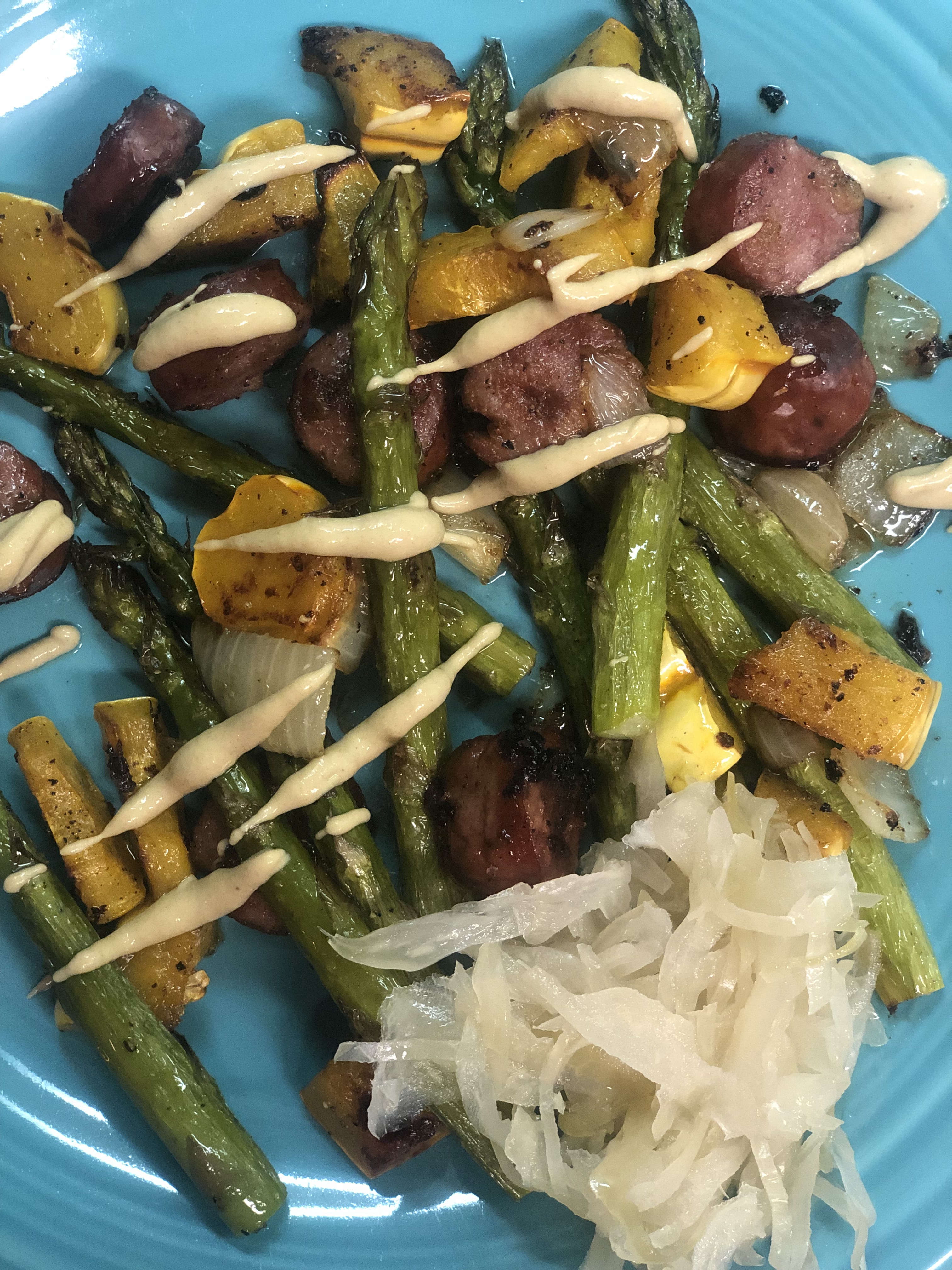 Roasted sausage, asparagus, delicata squash and onion with kraut and Dijon mustard on a blue plate